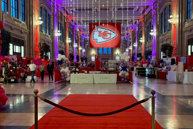 Photo of Union Station showing a velvet rope in front of a Kansas City Chiefs flag and several tables set up for the KC Love event.