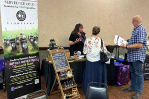 Photo of a presentation booth with one person behind a table and two customers in front.