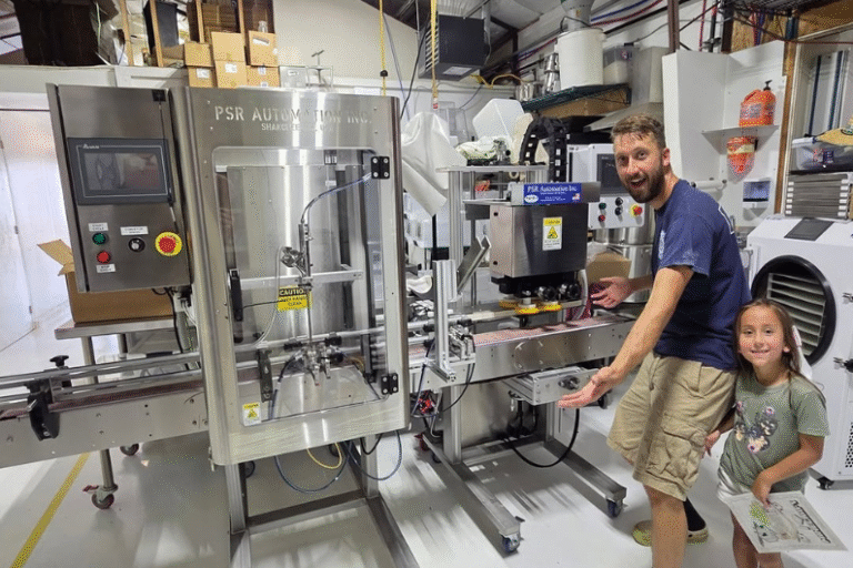 Photo of Eric Myers and his daughter standing in front of a bottling machine.